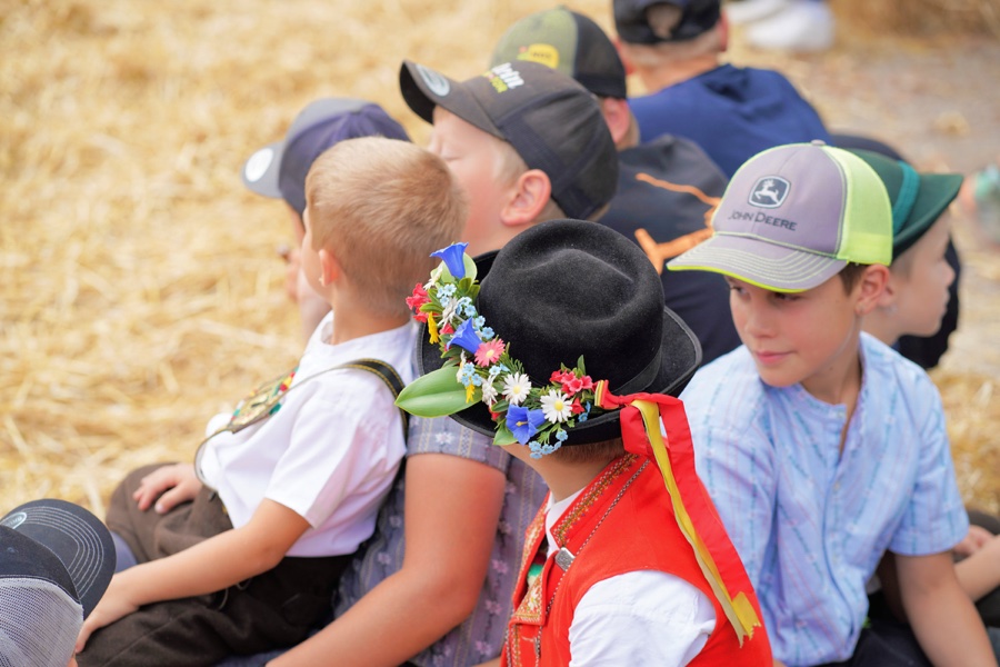 Seated children, including a child wearing a black hat decorated with flowers.