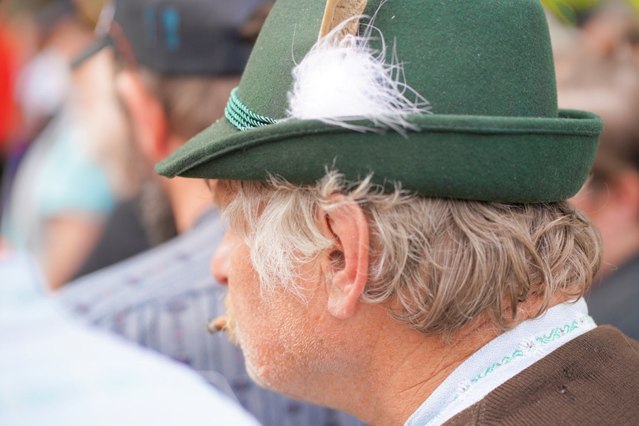 Side portrait of a man wearing a green felt hat with a white feather.