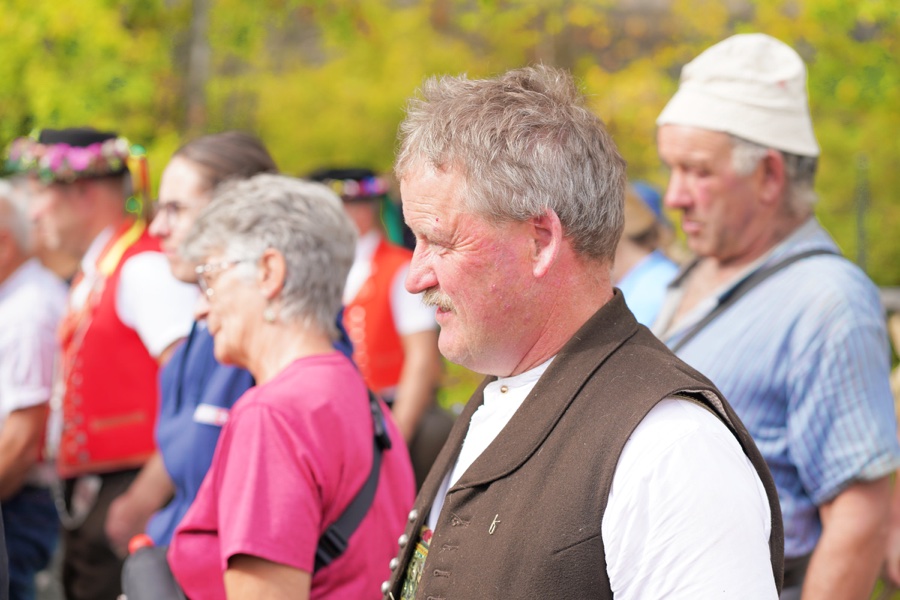A man wearing a dark waistcoat and a white shirt among other visitors.