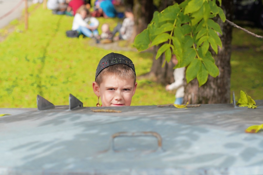 A child wearing a dark cap looks over a metal edge.