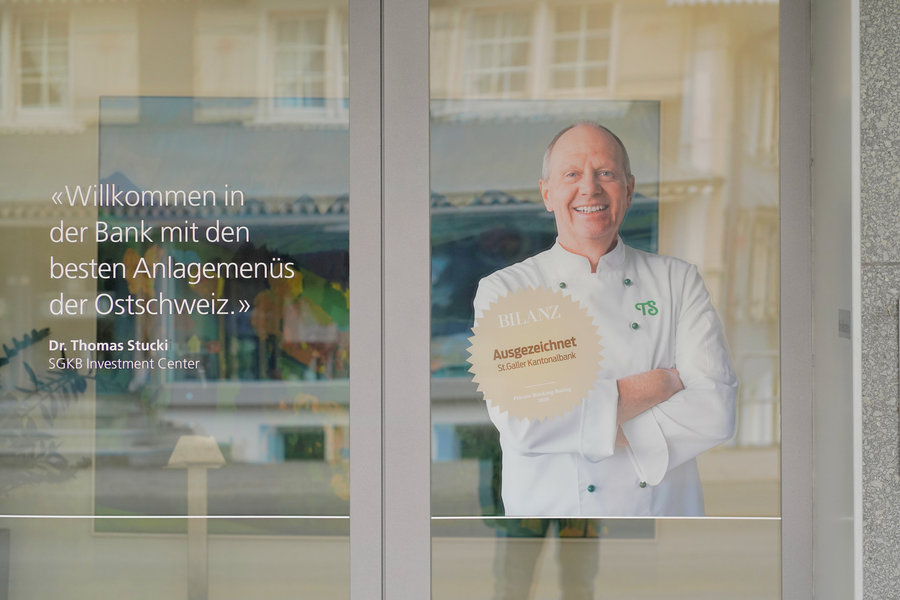 An advertisement showing a smiling man and lettering behind a glass door that reflects nearby houses.
